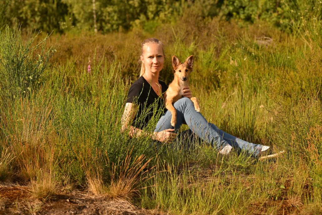 Dorothea Johnen sitzt im Gras mit Kiwi auf dem Schoss, einer Silken Windsprite-Hündin aus einer Outcross-Verpaarung mit einem Sheltie-Vater).